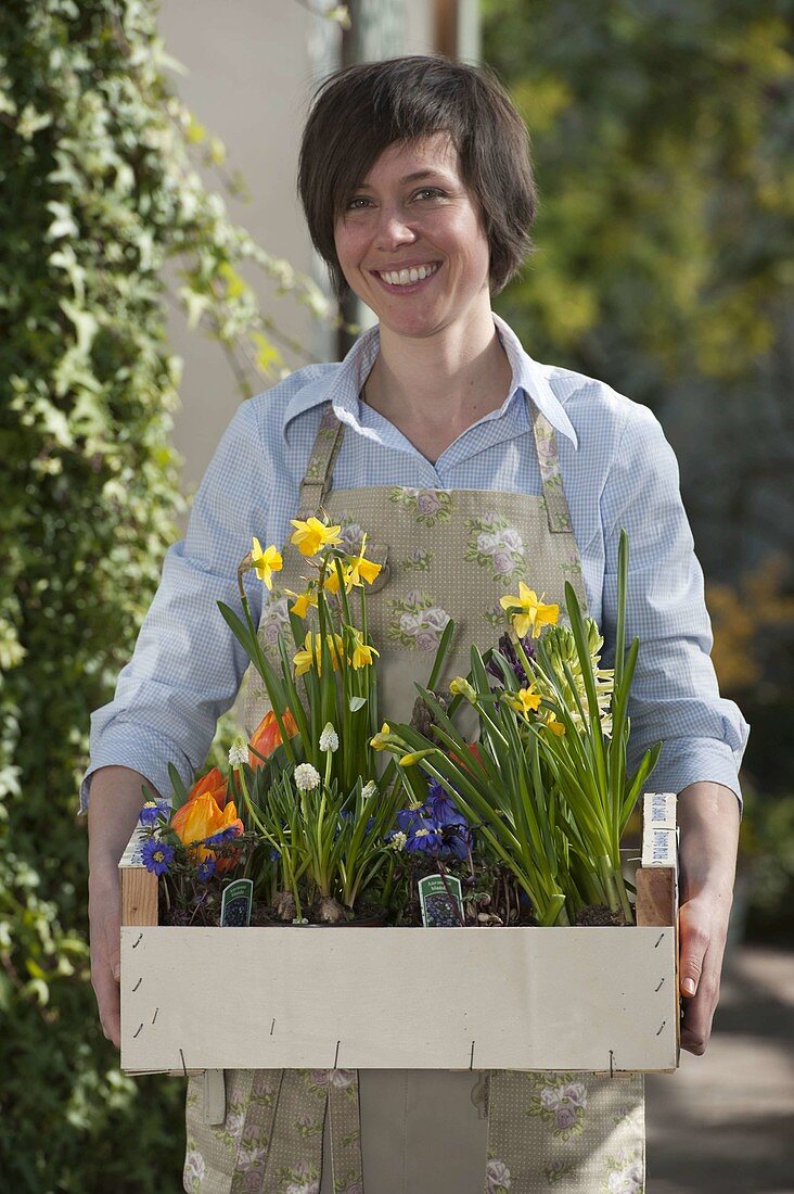 Woman with fruit box full of spring bloomers