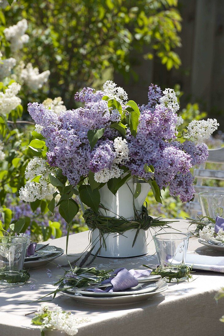 Lilac table decoration in the garden in front of lilac bushes