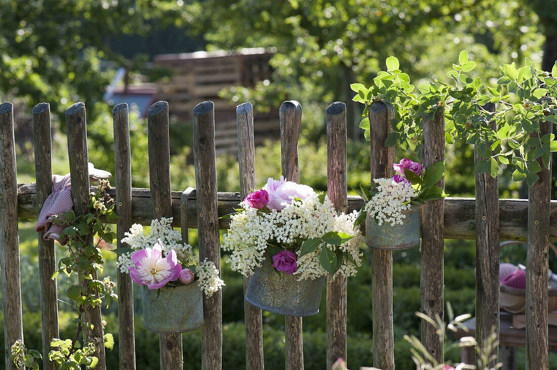 Small bouquets in metal pots hung on a fence