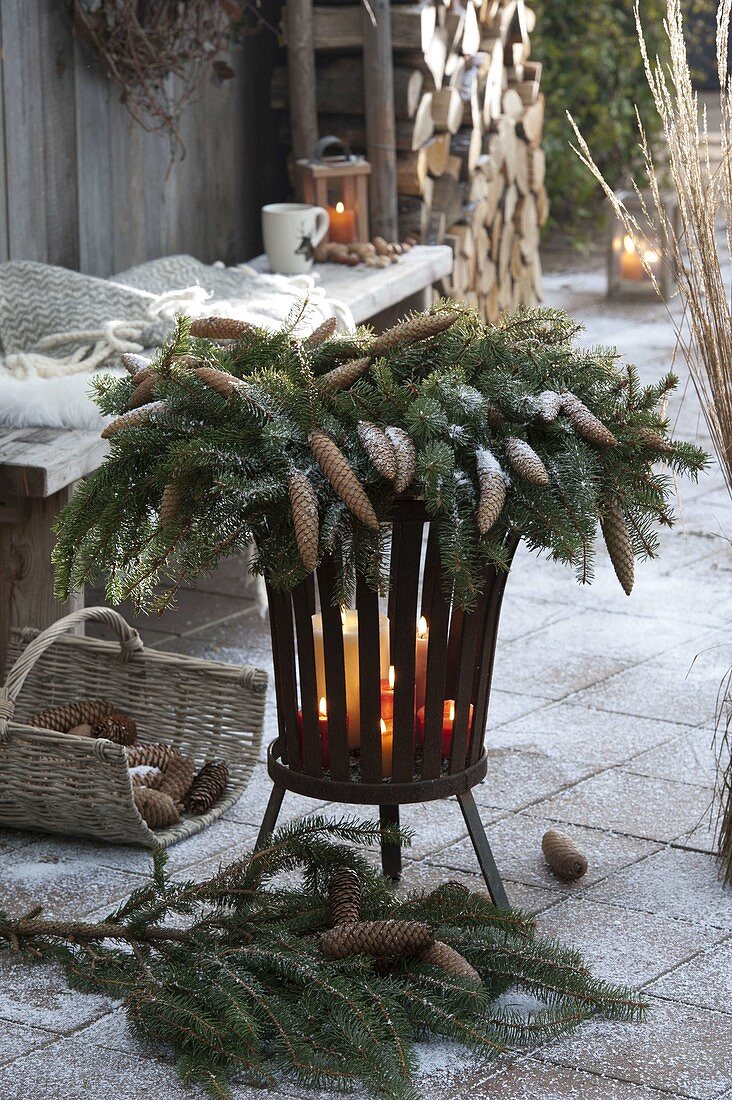 Wreath of Picea omorica with cones on fire basket with candles