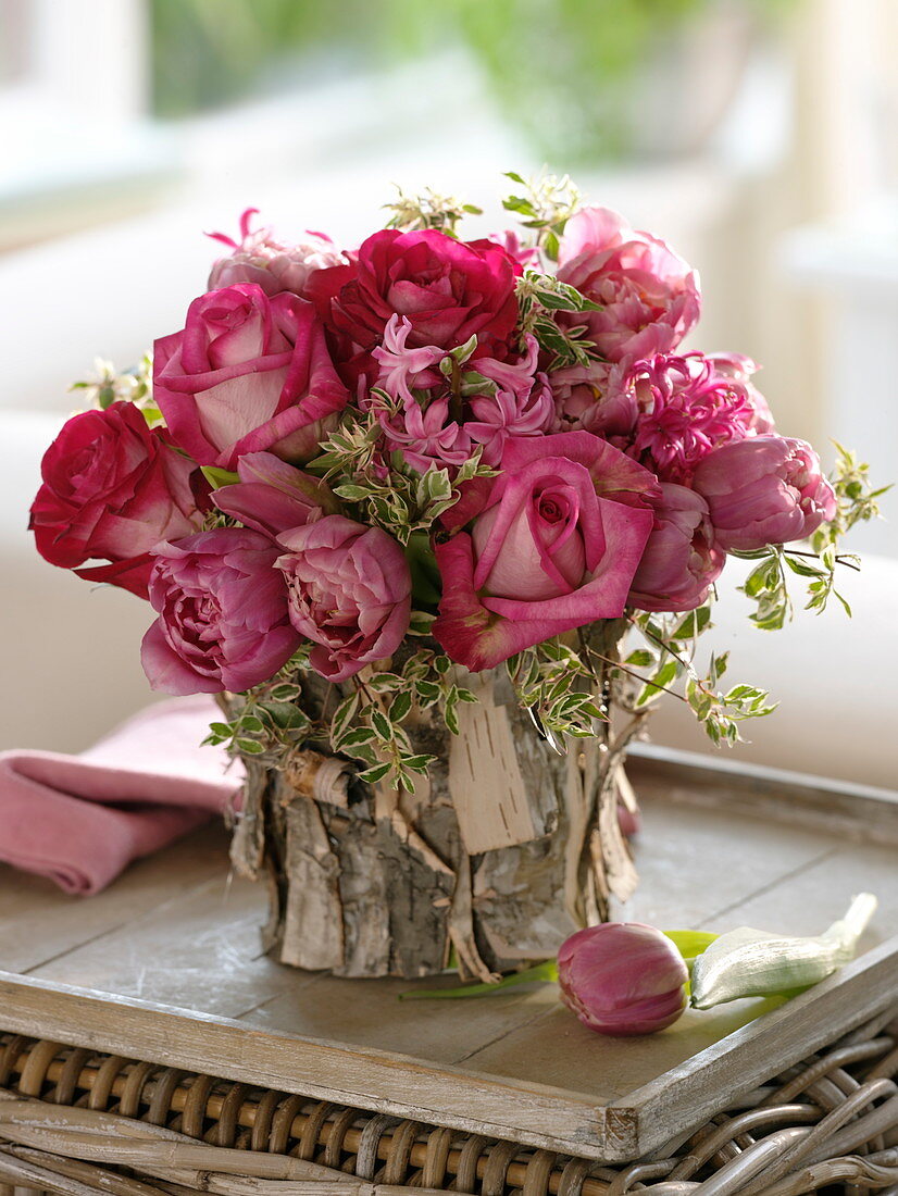 Pink-red spring bouquet in bark-clad vase