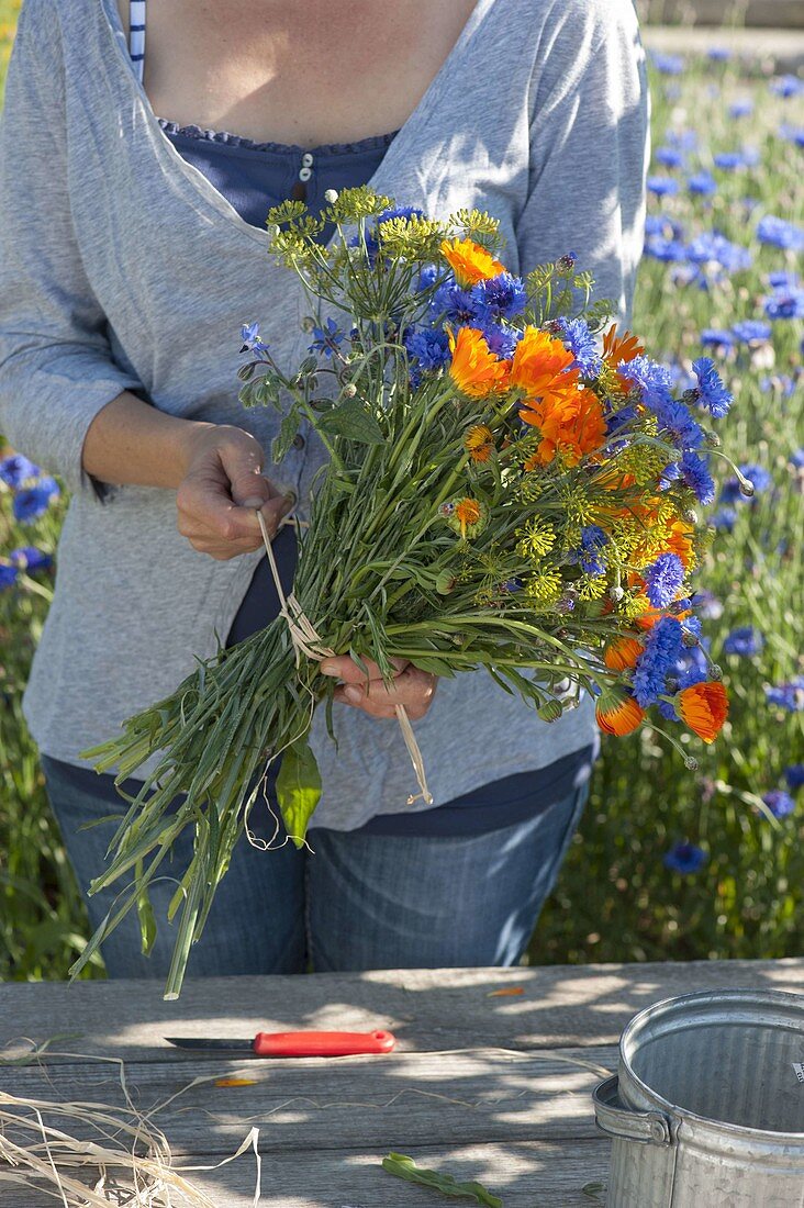 Tying blue-orange summer flower bouquet