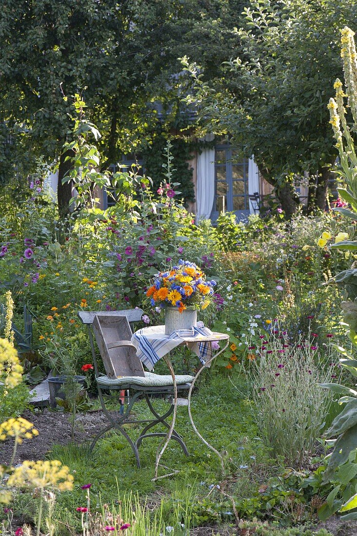 Small seating area between flower beds with perennials and summer flowers
