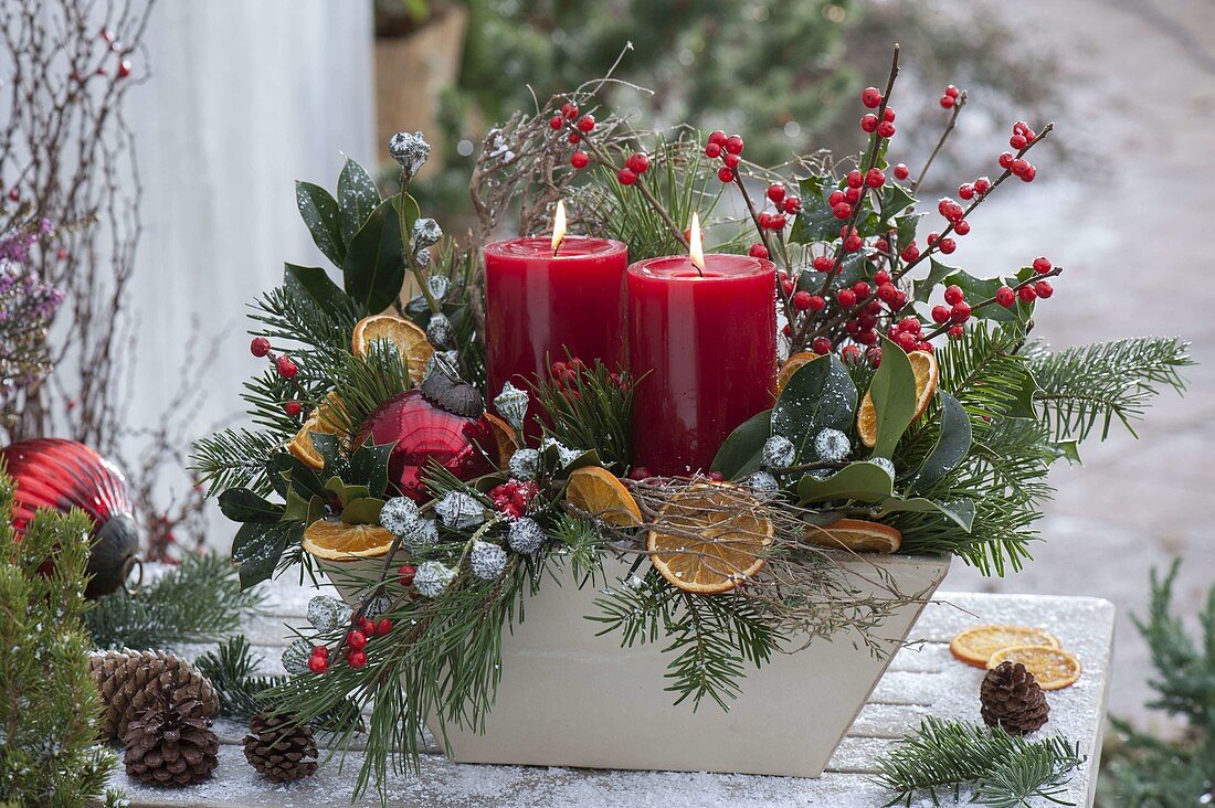 Christmas candle arrangement with roses, branches of Ilex
