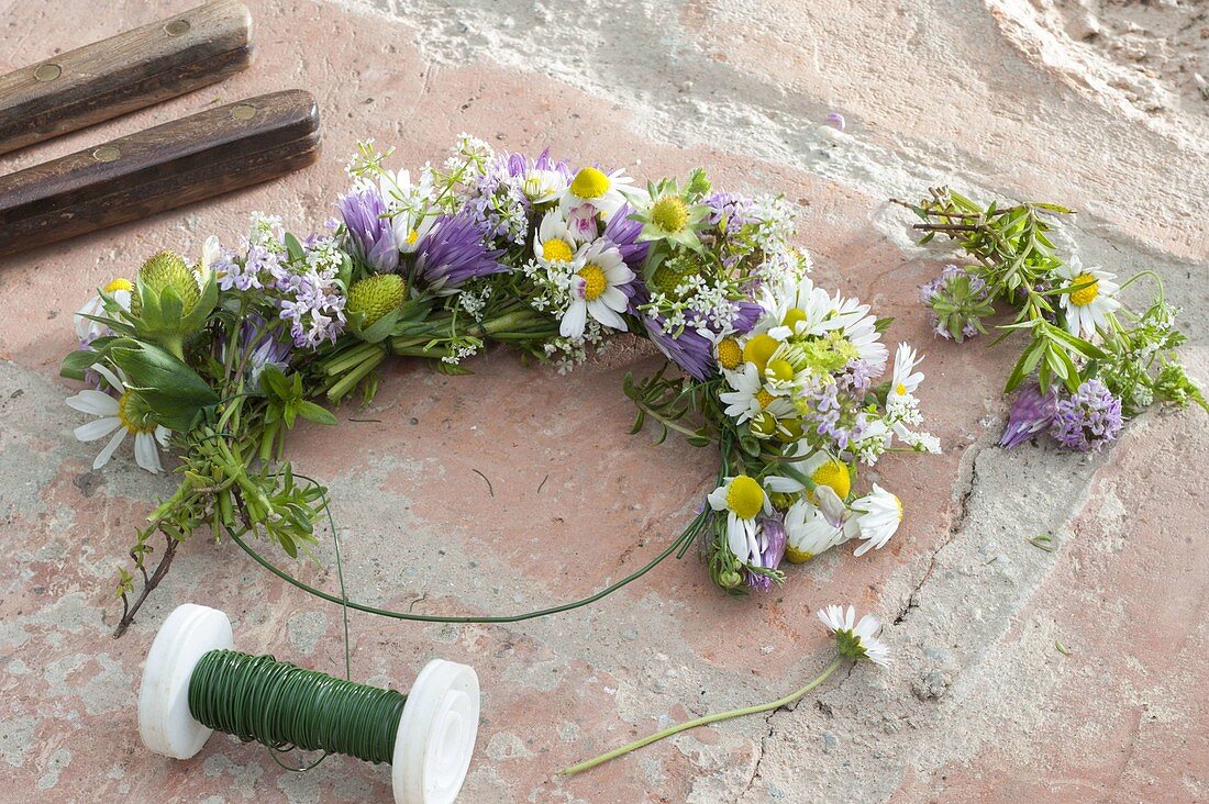 Tying a wreath of flowering herbs and strawberries