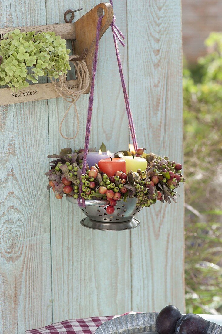 Wreath with burning candles hung in a kitchen colander
