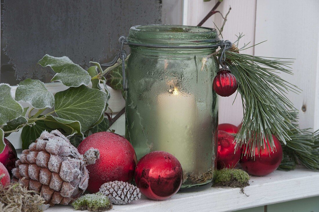 Preserving jar as a lantern on the windowsill with red balls