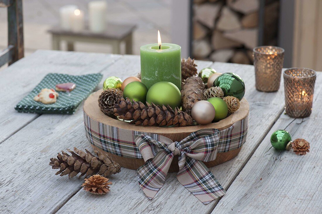 Adventliche Deko mit grüner Kerze, Kugeln und Zapfen in Holz-Schale