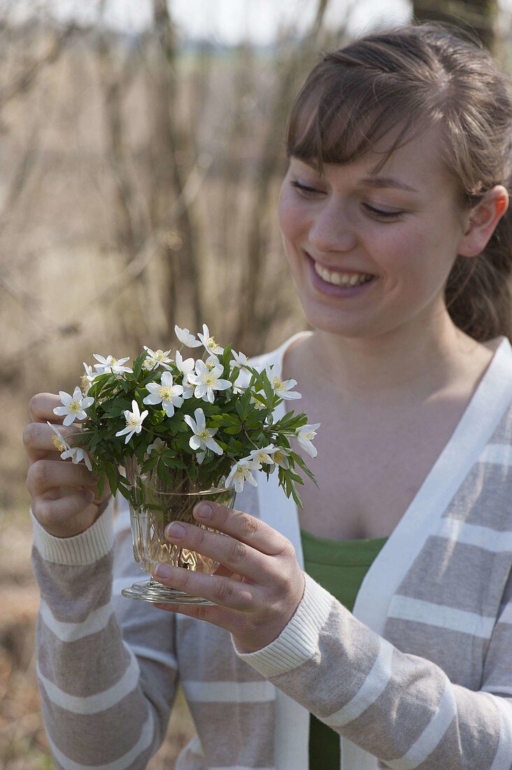 Woman with a little Anemone nemorosa (Wood anemone) bouquet