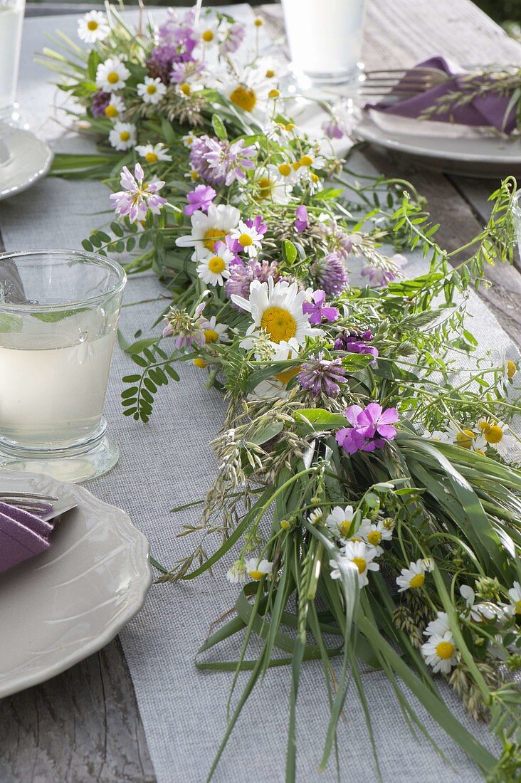 Early summer table decoration grass plait as table garland decorated with camomile