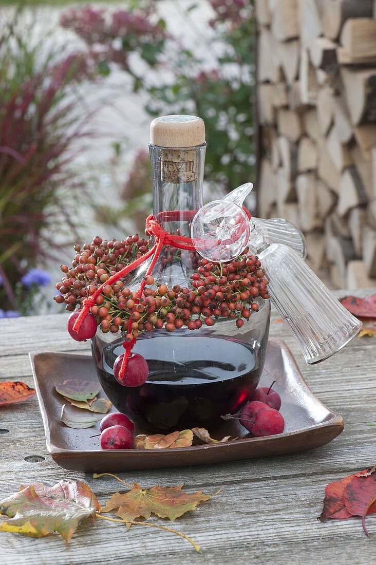 Bottle of red wine liqueur as a gift with a rosehips bouquet