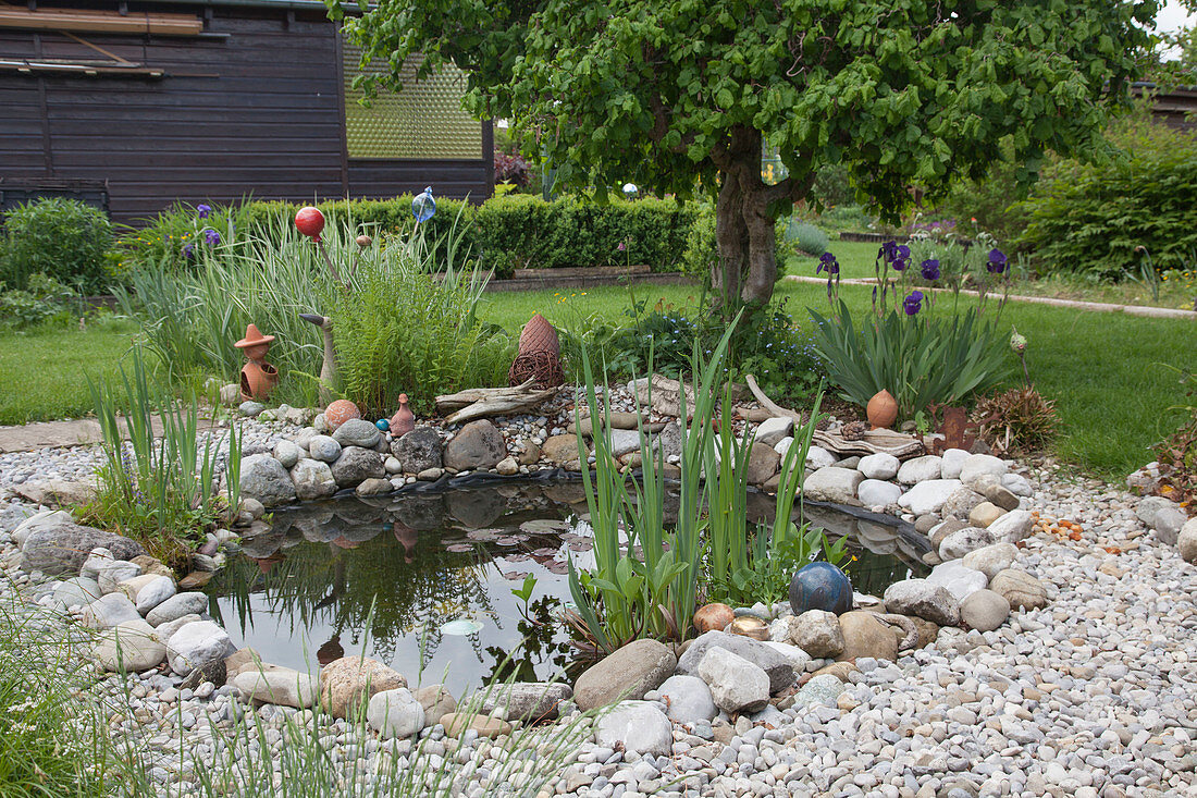 Kleiner Folienteich mit Natursteinen eingefasst im Garten