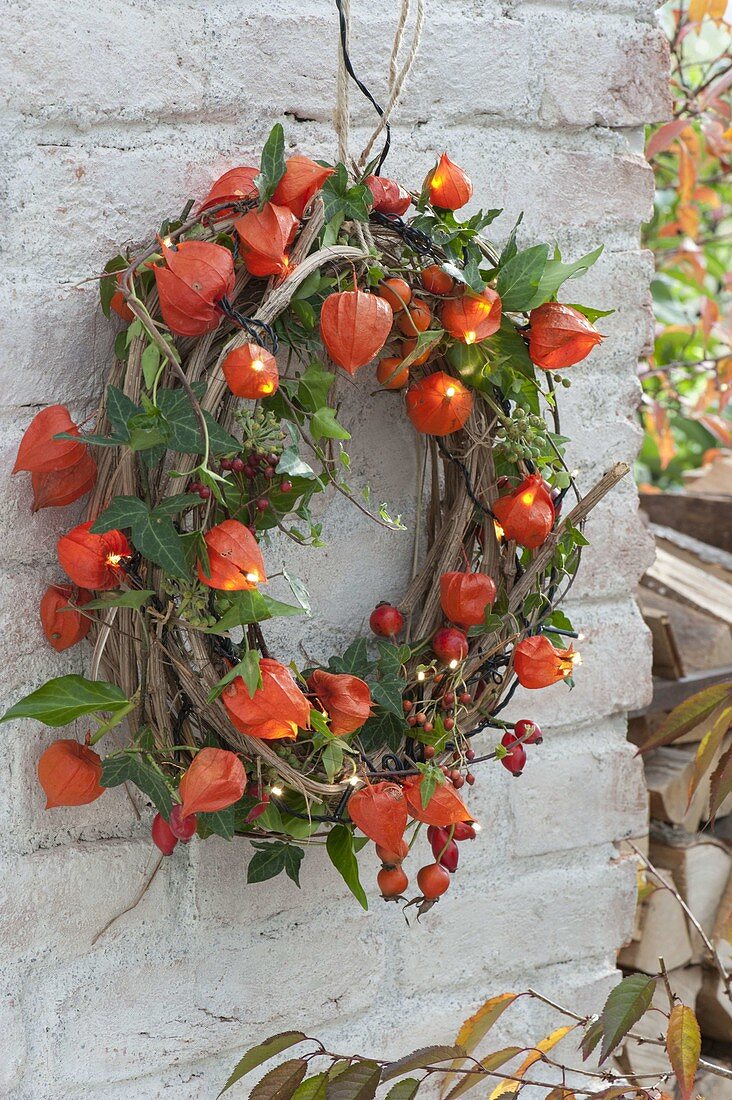 Beleuchteter Clematiskranz mit Lichterkette in Physalis (Lampions)