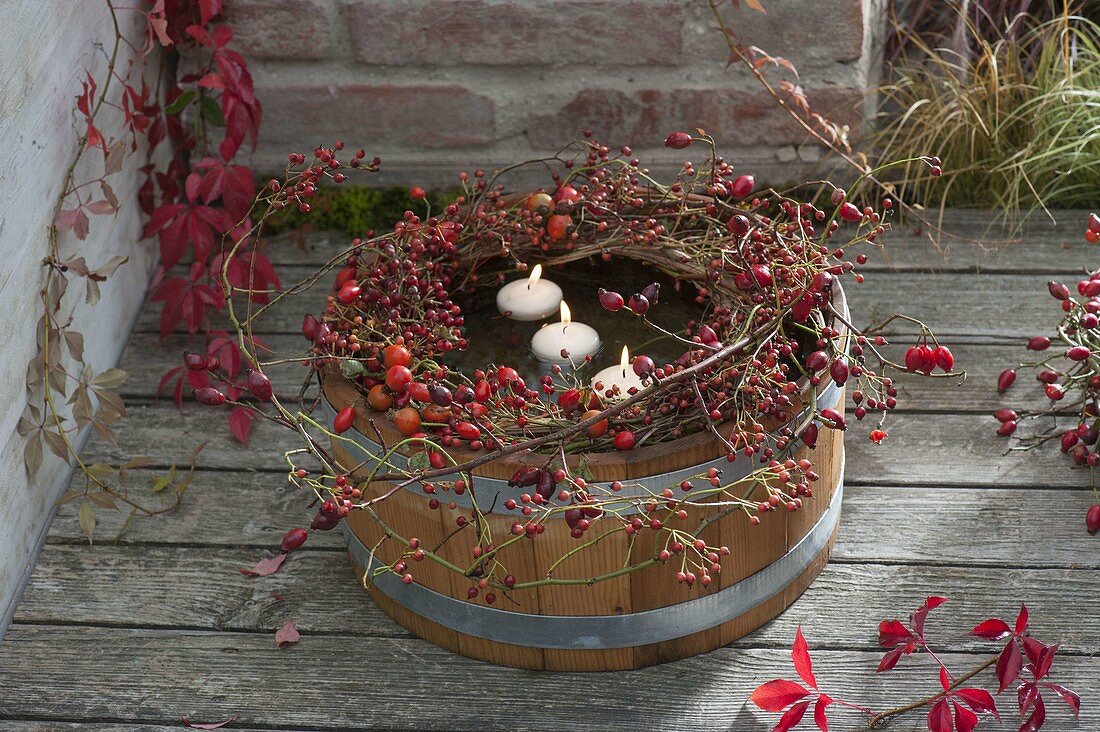 Wreath made of different roses (rosehip) on wooden barrel with water