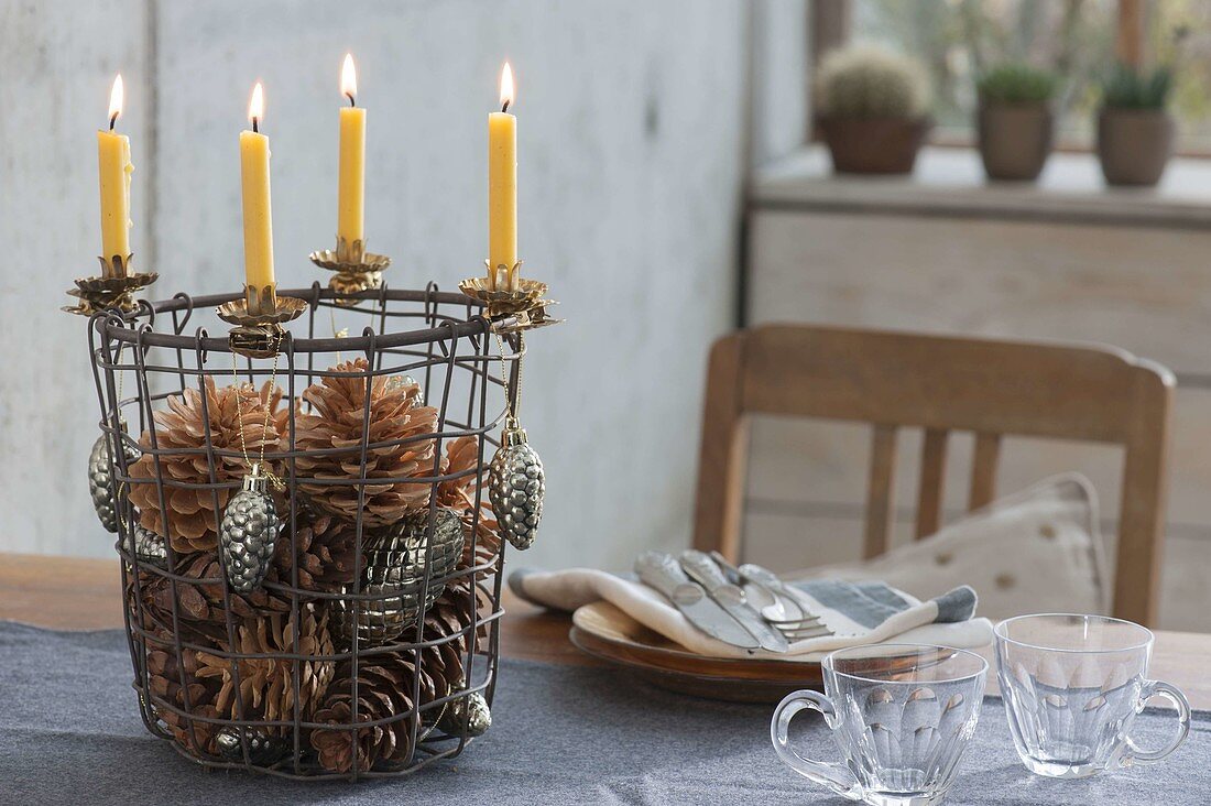 Drahtkorb als 5-Minuten-Adventskranz mit gelben Kerzen, Zapfen