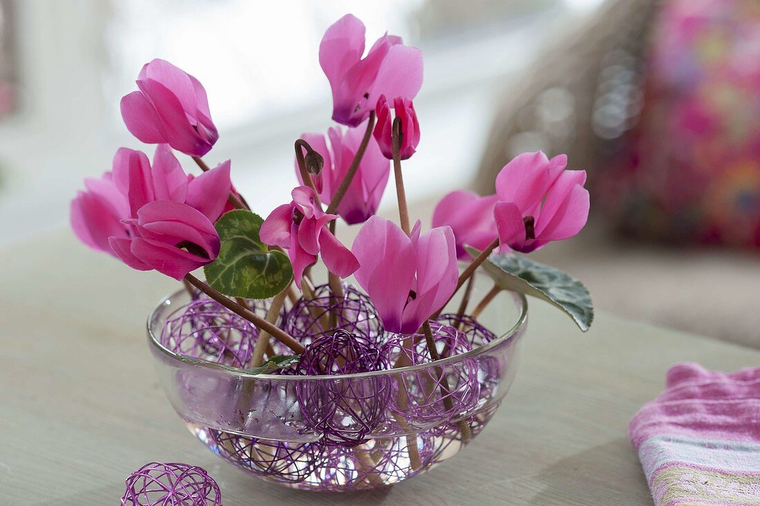 Violette Kugeln aus Draht in Glasschale als Steckhilfe für Blüten und Blätter