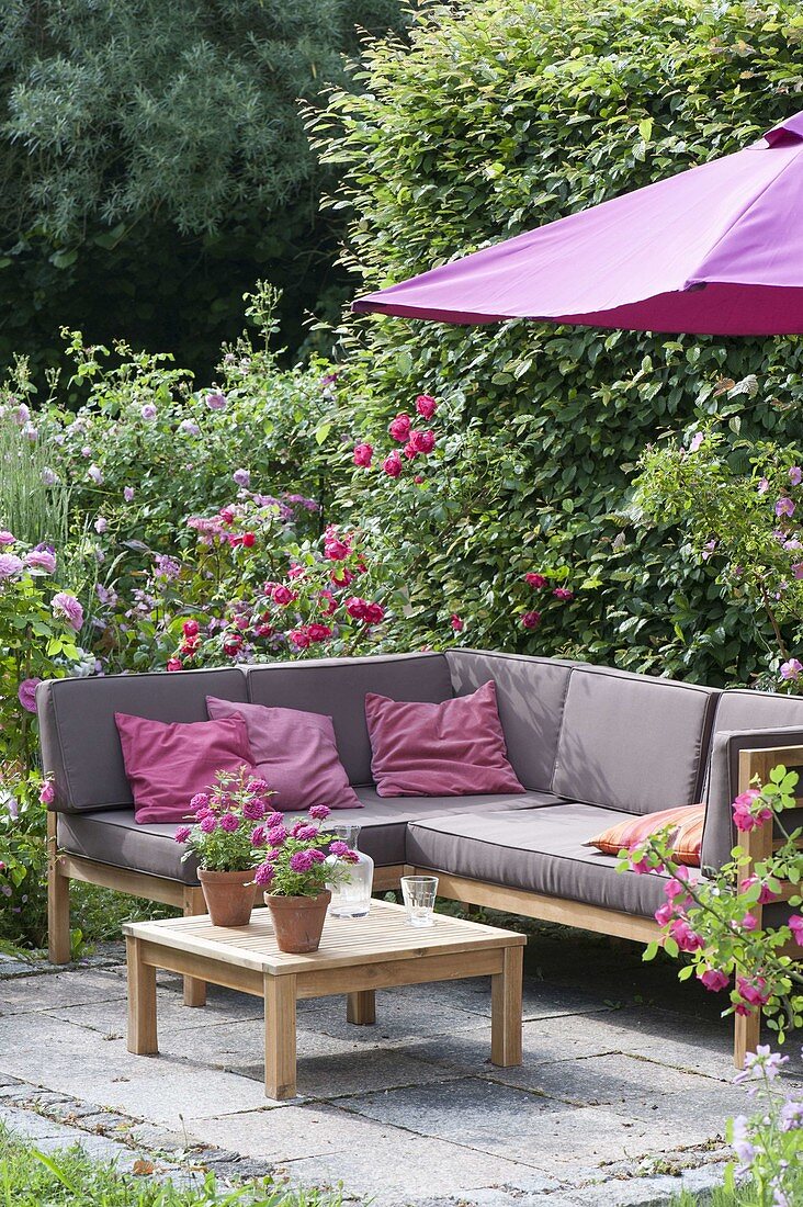 Lounge corner on small terrace between roses