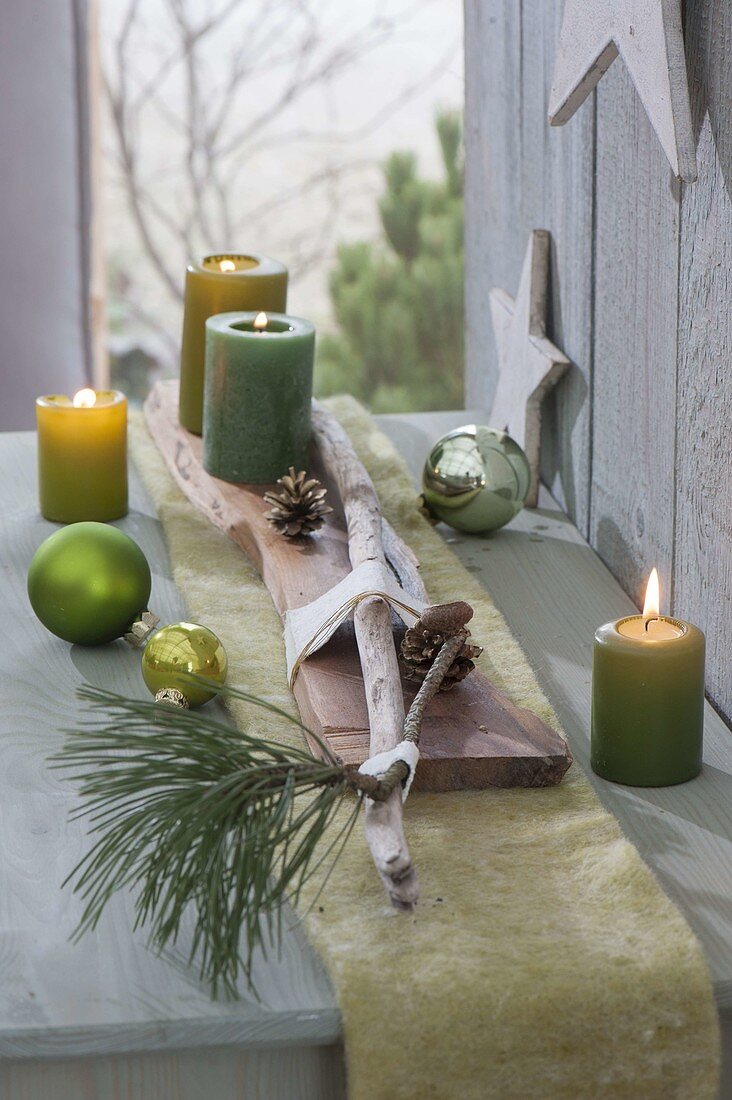 Board with green candles, driftwood, cones and pinus branches