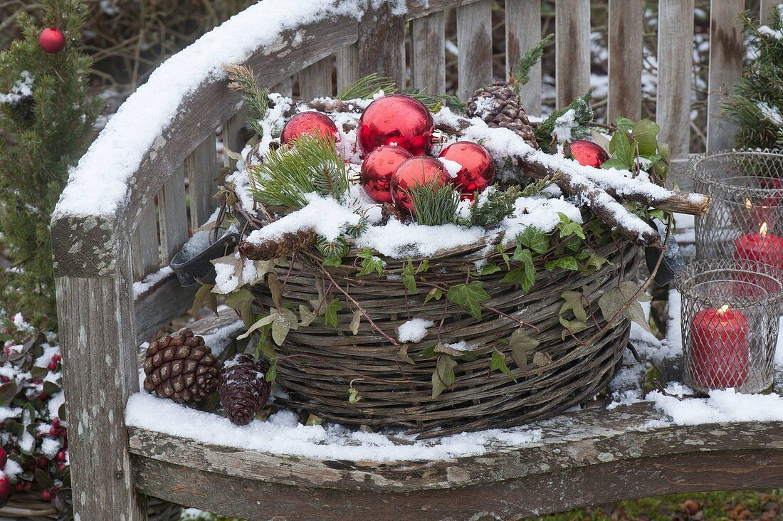 Basket with coniferous branches, cones and red baubles