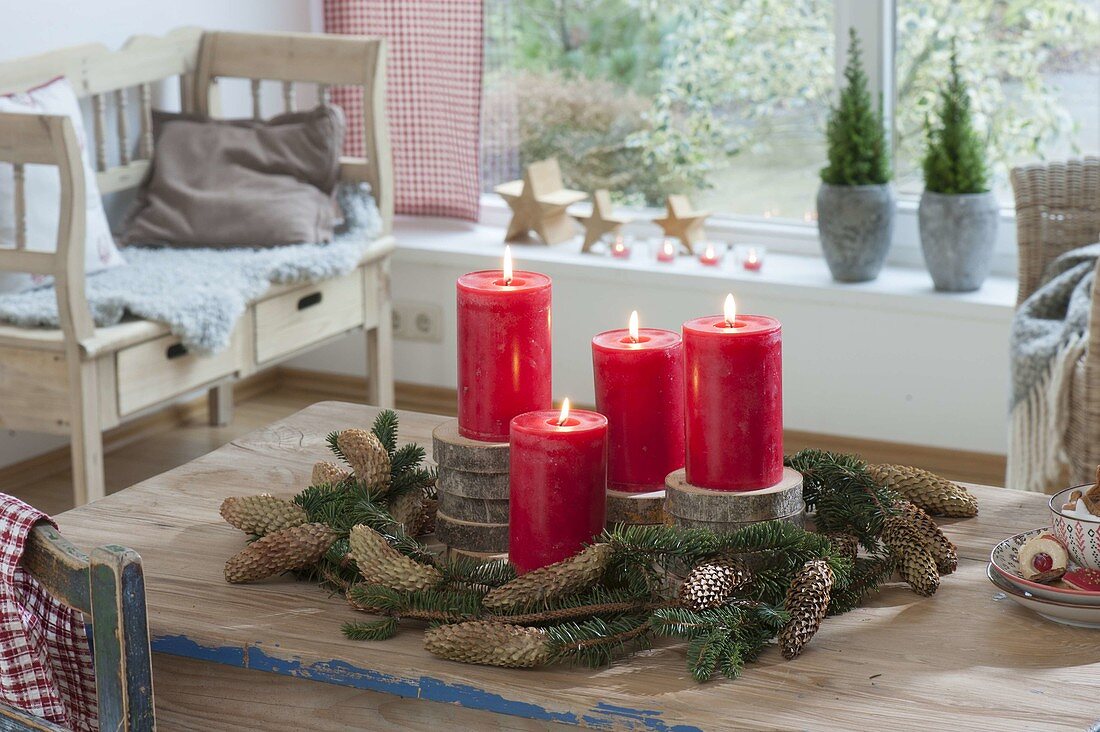 Schlichte Adventsdeko mit roten Kerzen auf Holzscheiben