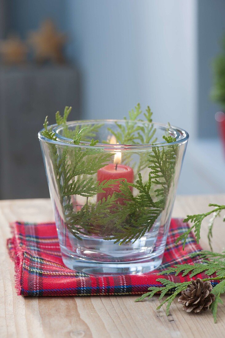 Glass with red candle as lantern, decorated with thuja