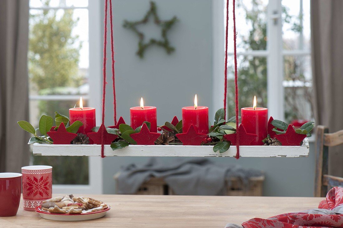 Hängender Adventskranz auf Holzuntersetzer über dem Tisch