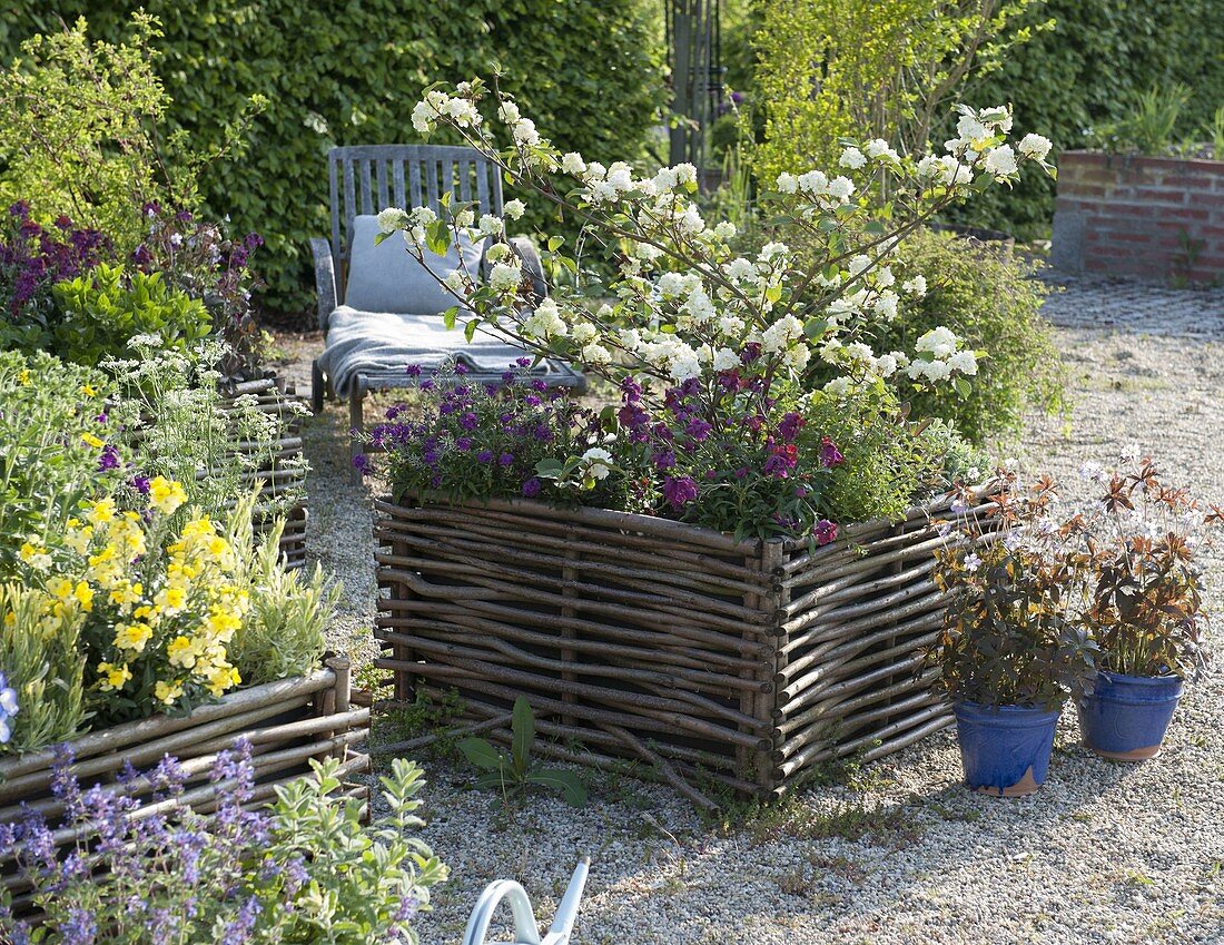Gravel terrassse with raised beds made of hazelnut rods