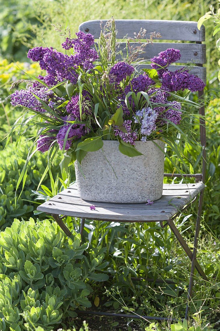 Lush Syringa bouquet with grasses in rustic jardiniere