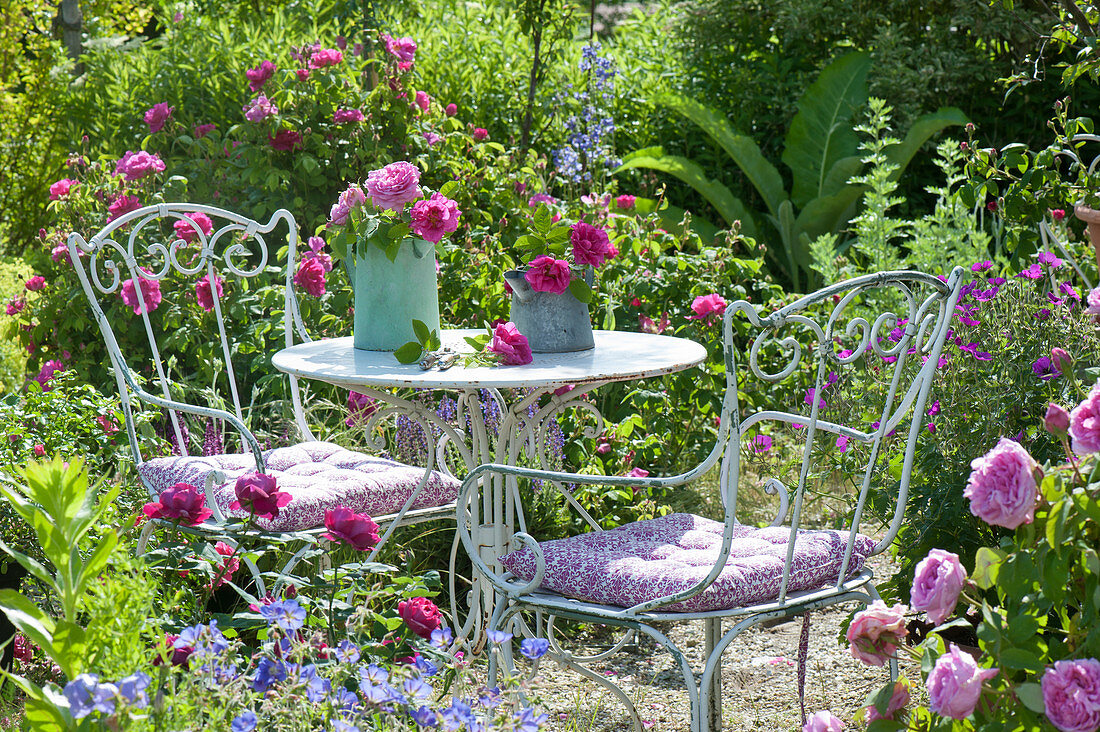 Sitzplatz im Rosengarten zwischen bluehenden Beeten