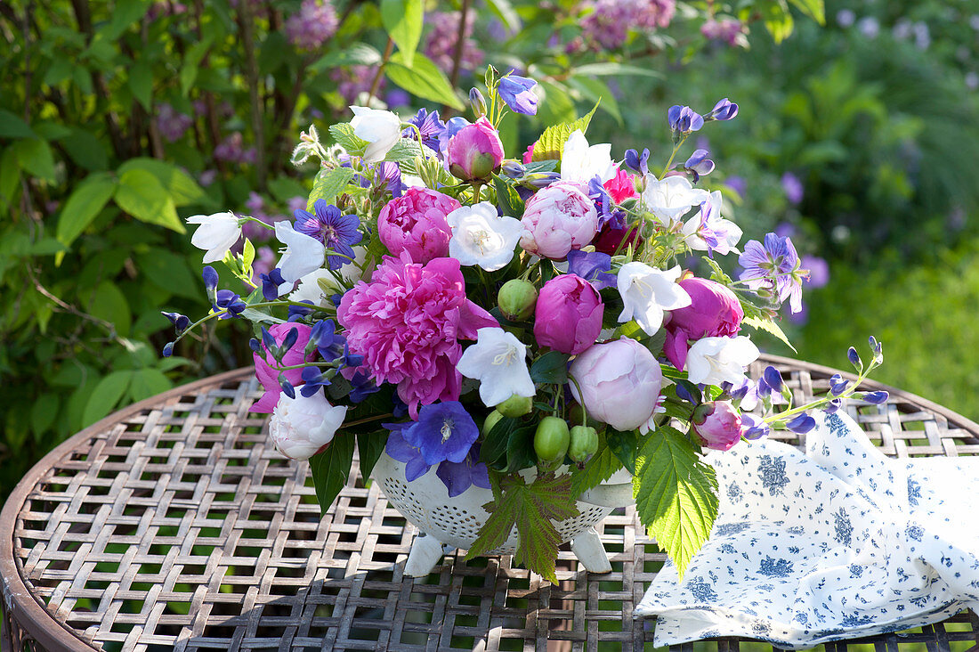 Arrangement made of Paeonia (Peony), Campanula in the enameled sieve