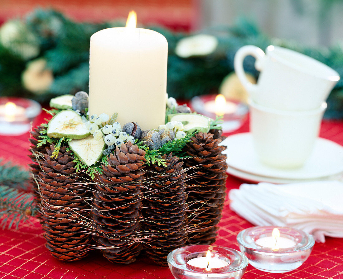 Candle decoration decorated with pine cone, clay pot with pine cones and fruits