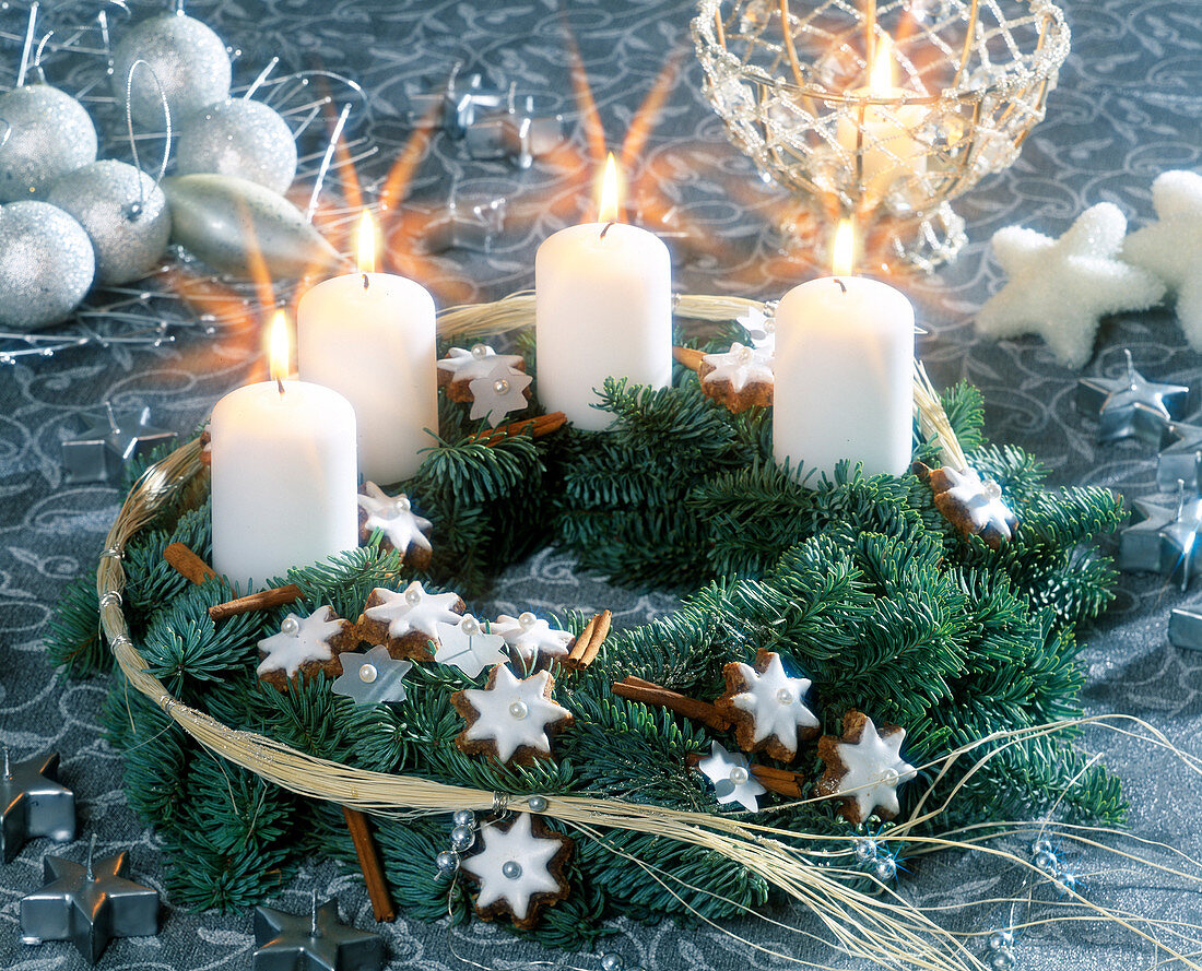 Adventskranz aus Tannenzweigen, Zimtsternen und weißen Kerzen
