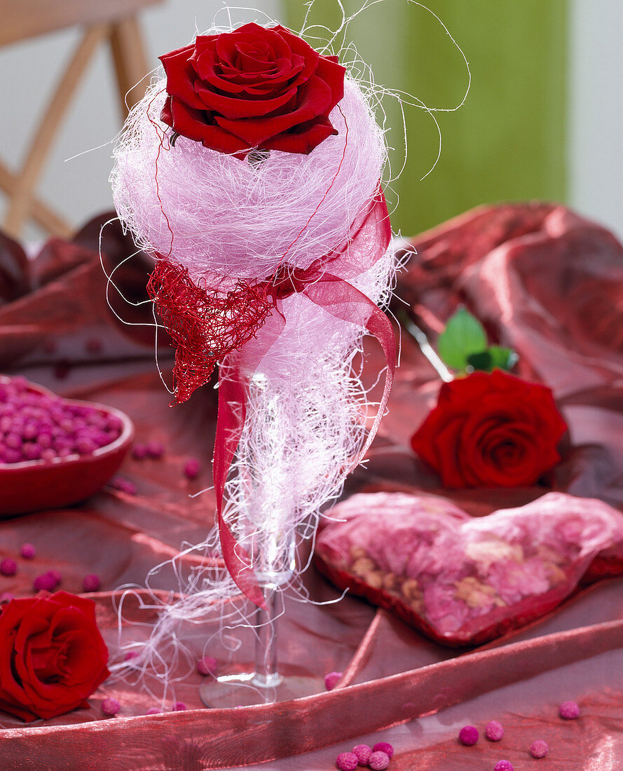 Glass vase with red rose, sisal nest and raffia heart