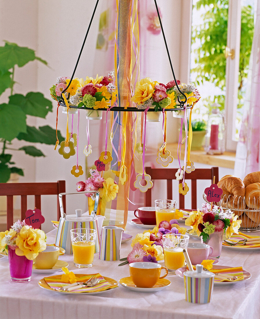 Frühlingshafte Tischdeko: Drahtgestell mit kleinen Gläschen und Blüten von Belli
