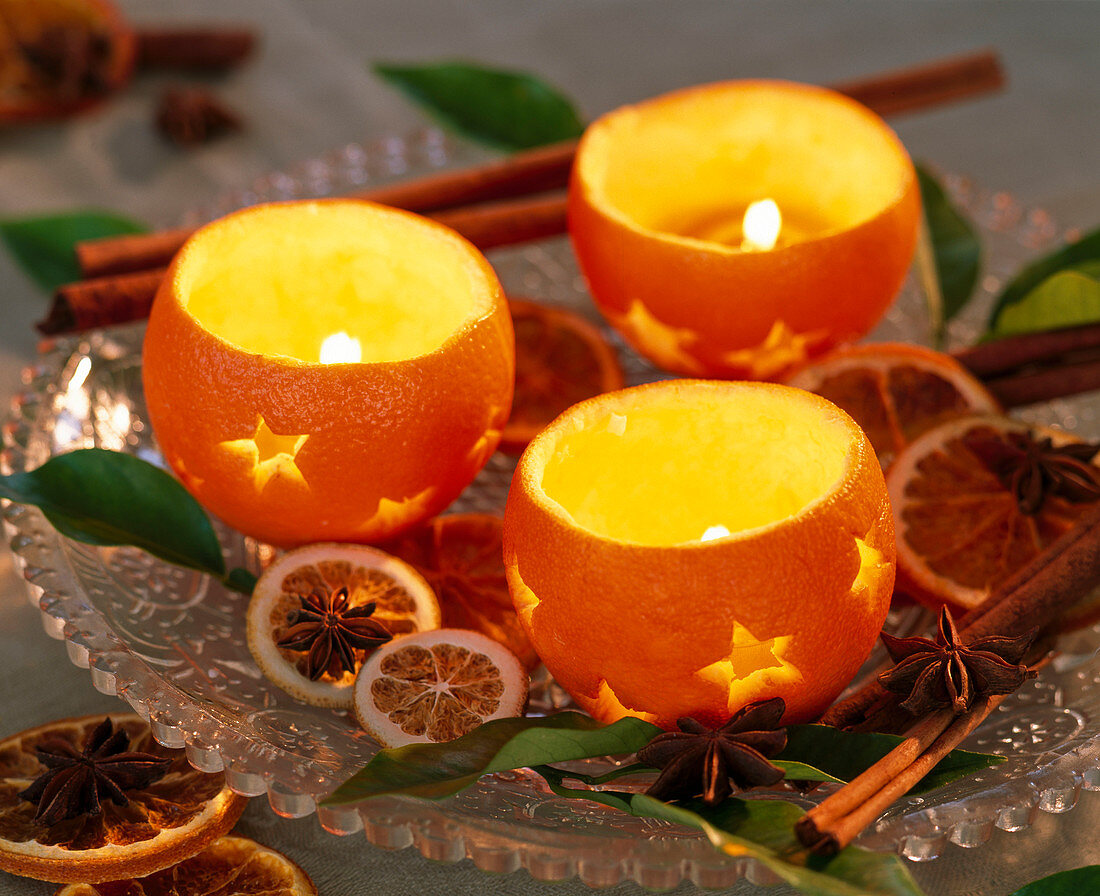 Citrus oranges hollowed out as tealight holders, slices of orange, leaves, star