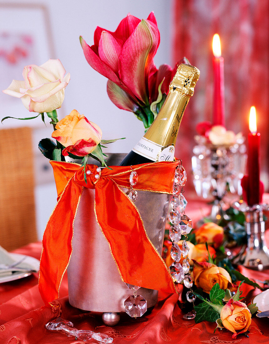 Rose, hippeastrum (amaryllis) in champagne cooler, orange ribbon, glass