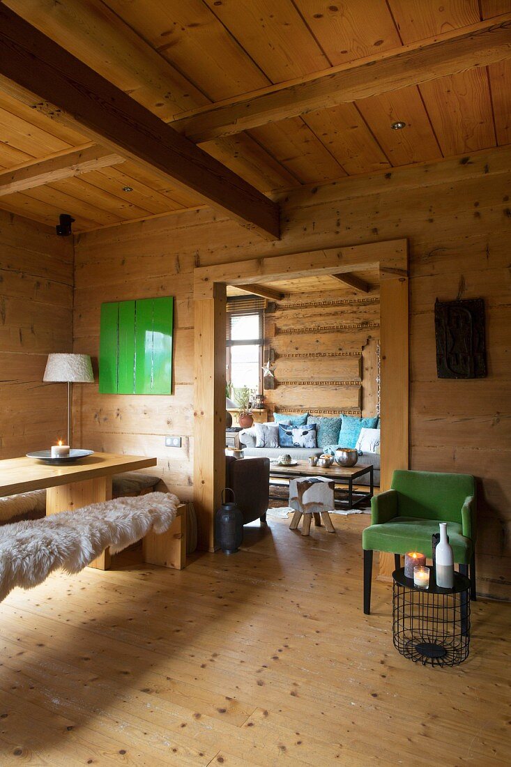 Green retro armchair, wooden table and sheepskin rugs on wooden bench in dacha