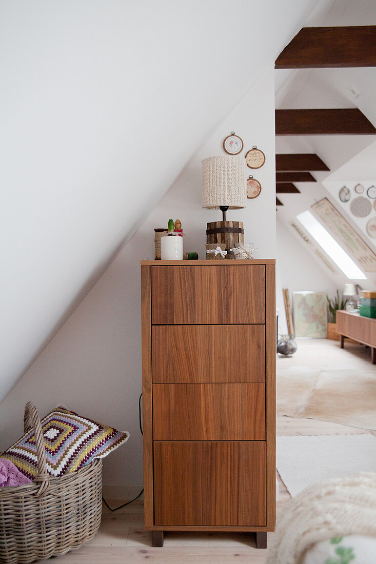 Chest of drawers with wood-grained fronts below sloping ceiling