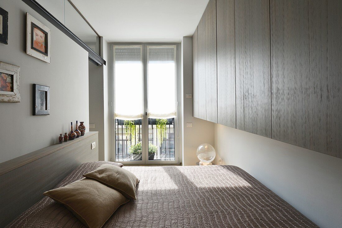 Custom wall-mounted cupboards and double bed in minimalist bedroom