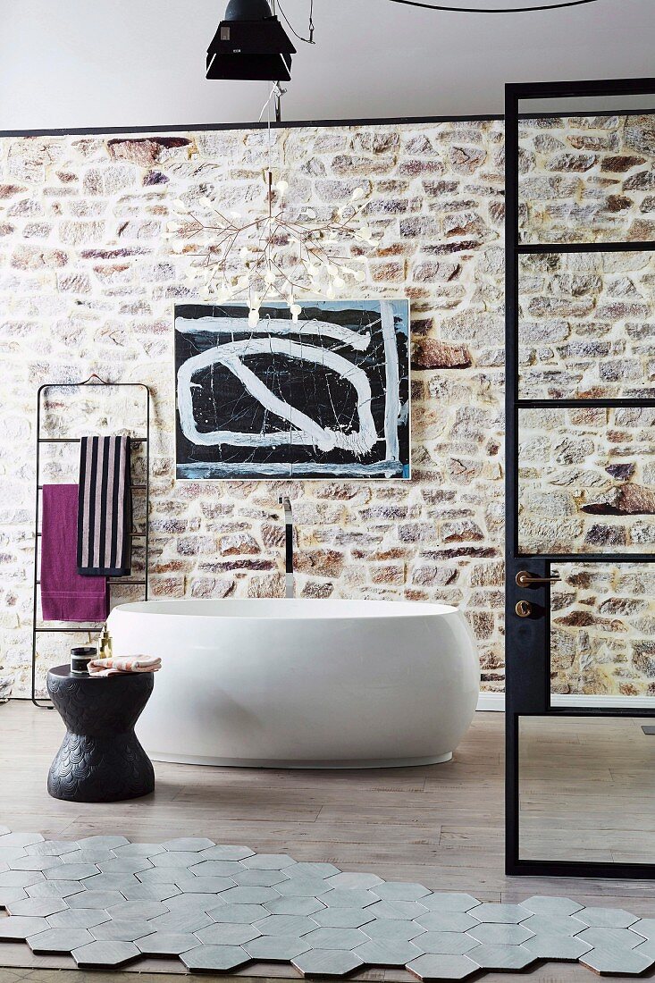 Modern freestanding tub in front of a wall with exposed brickwork