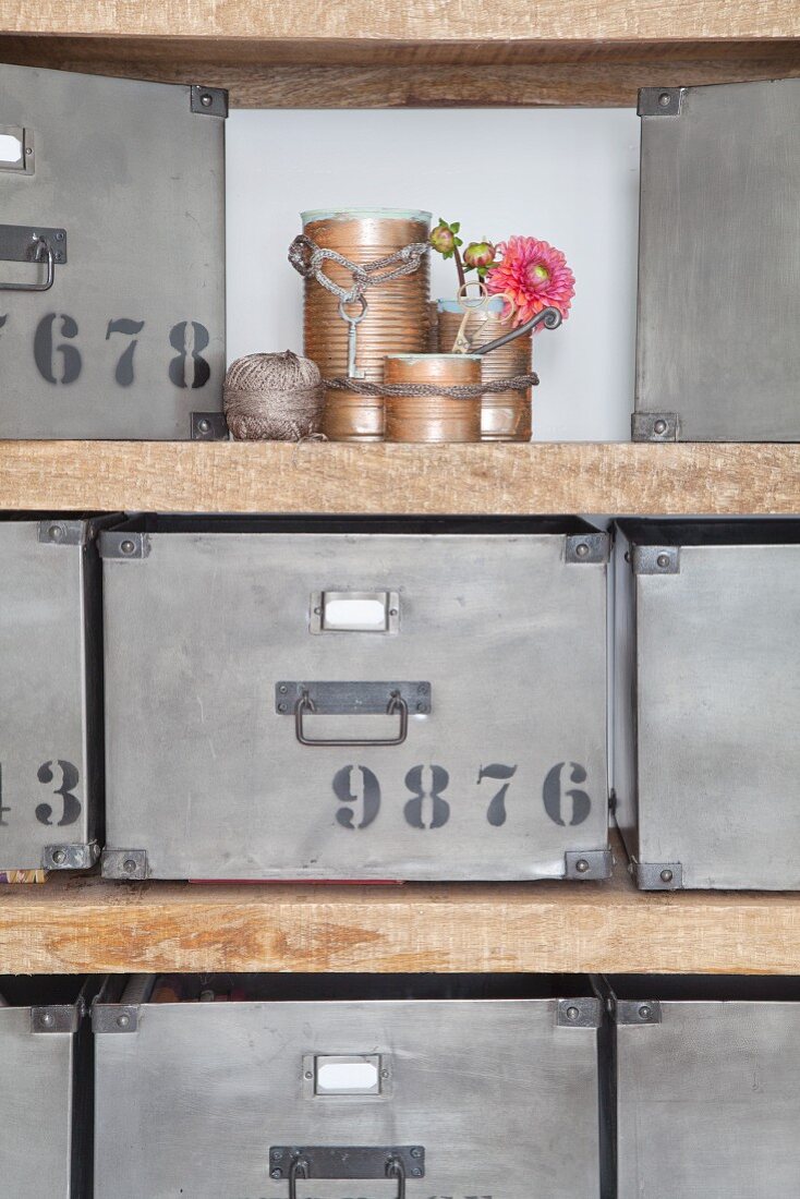 Recycled tin cans, knitted cords and retro metal storage boxes on open-fronted shelves