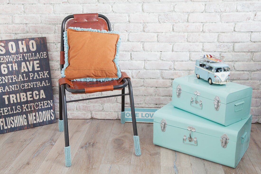 Mintfarbene Koffer, Lederstuhl mit gestrickten Stulpen und Retro-Schilder