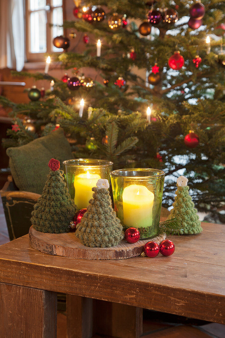 Gehäkelte Tannenbäume und Windlichter vor dem Weihnachtsbaum