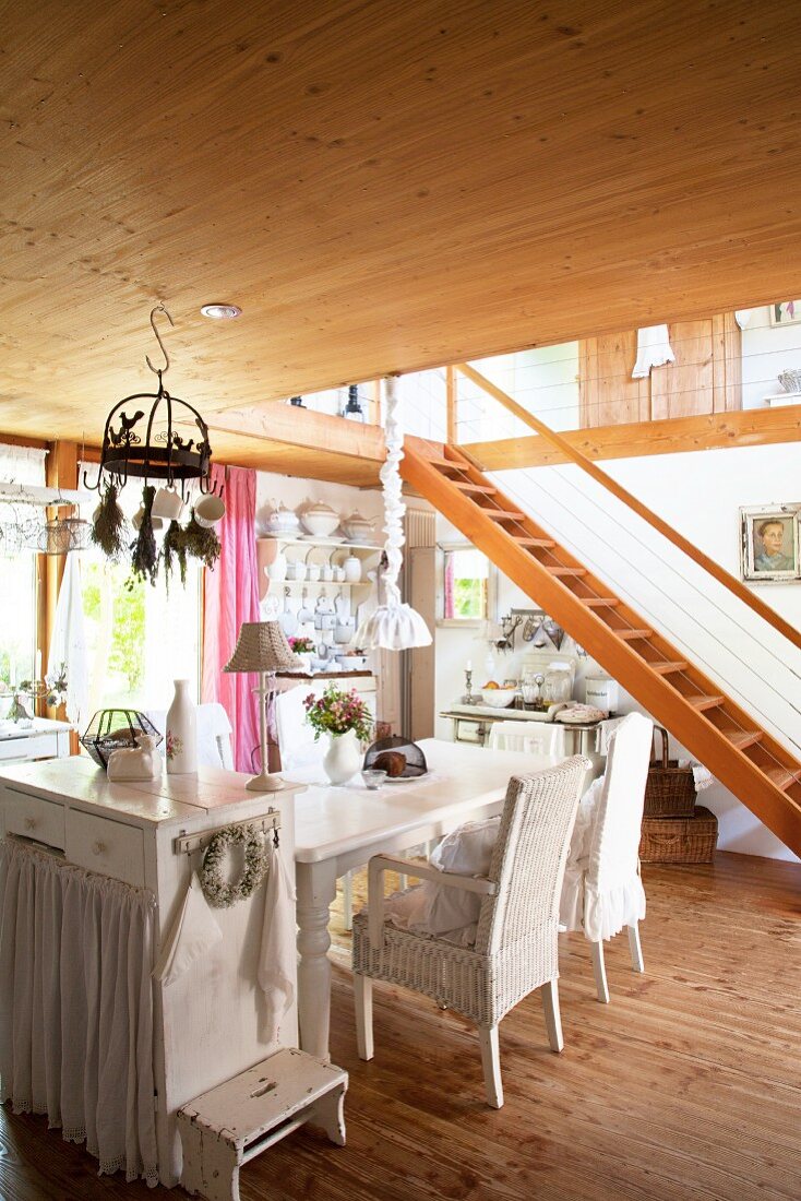 Offene Küche mit Shabby-Einrichtung, im Hintergrund Holztreppe zur Galerie