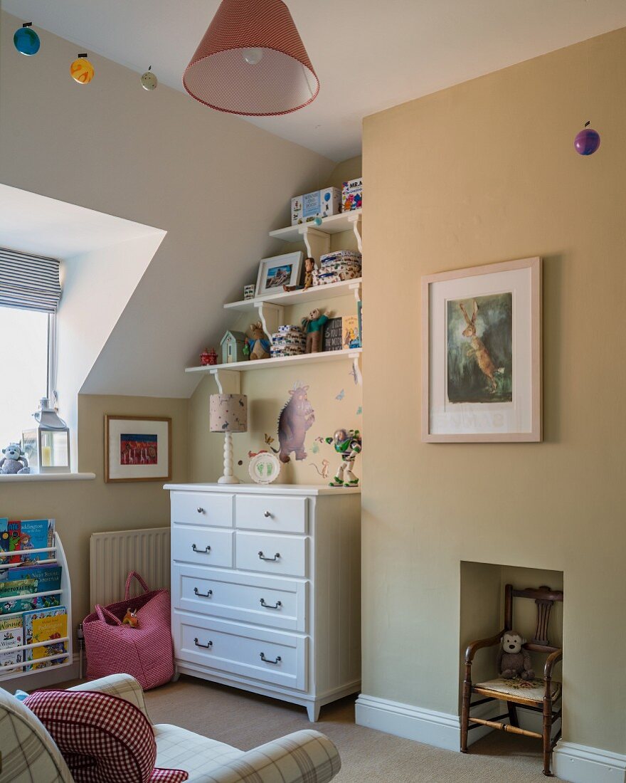Kinderzimmerecke mit weißer Schubladenkommode, Wandregal und antikem Kinderstuhl in Wandnische