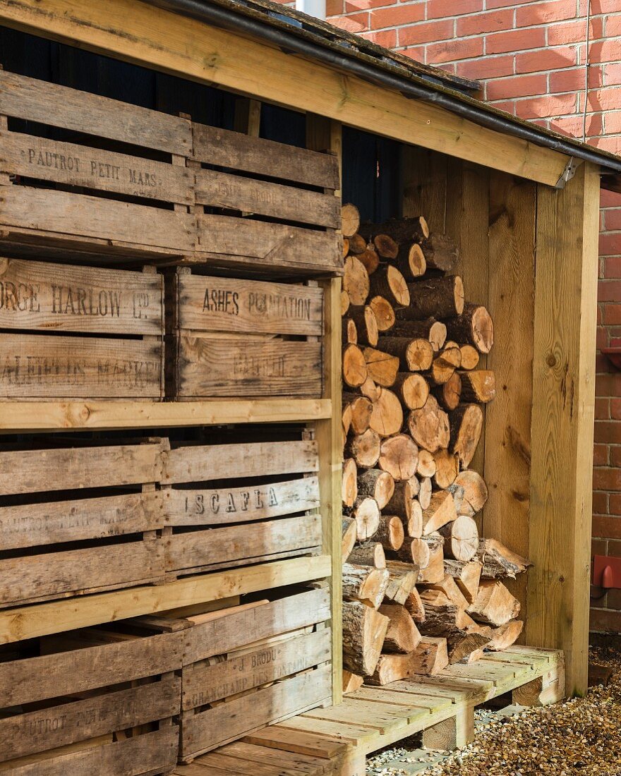 Weathered wooden crates next to stacked firewood in shed