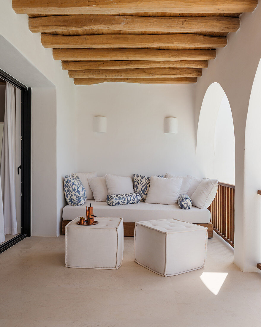 Sofa and pouffes in Mediterranean loggia with arcades