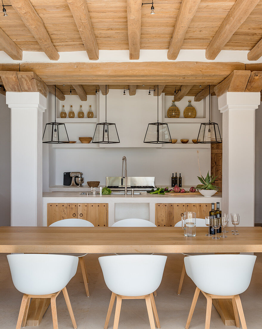 Esstisch mit modernen Schalenstühlen vor mediterraner Küche