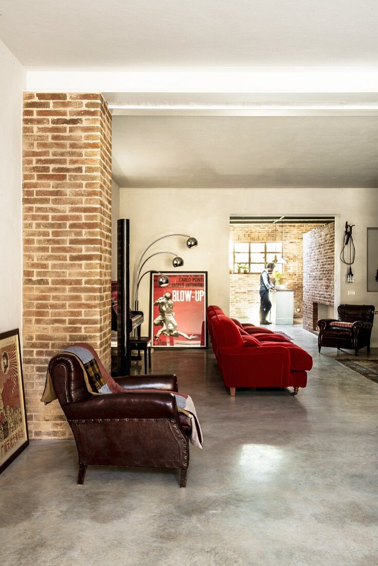 Wohnbereich mit Ledersessel und roter Couch, Blick in offene Küche