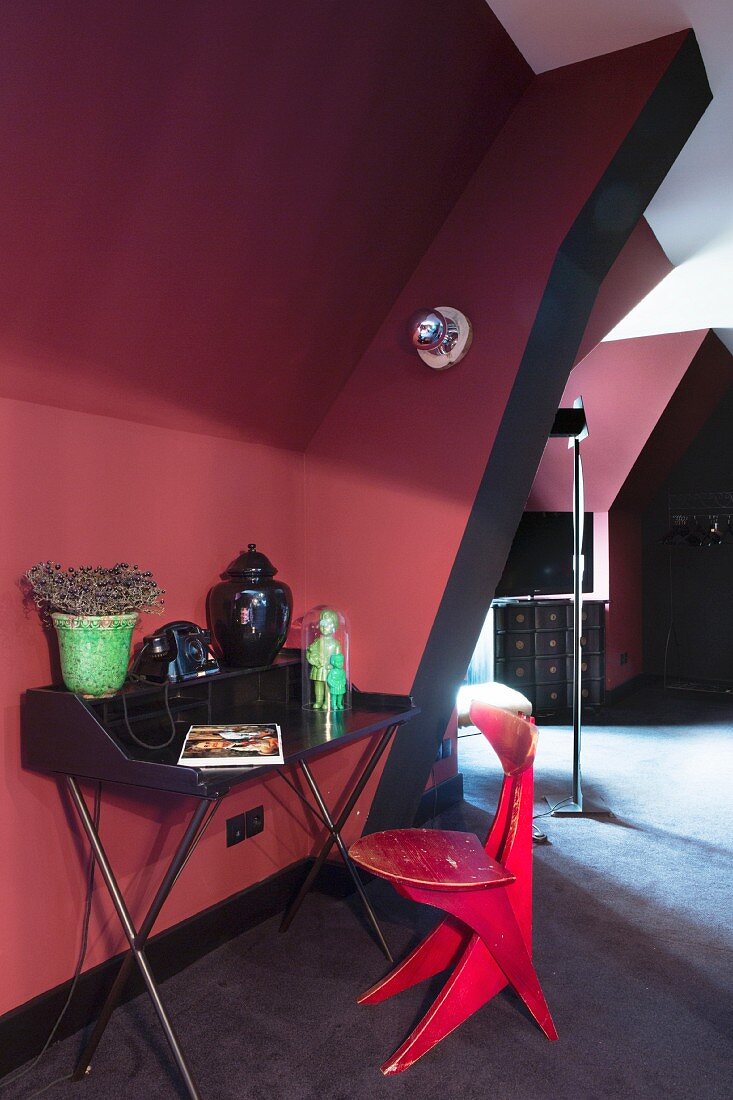 Schwarzer Retro Schreibtisch und roter Holzstuhl in Dachzimmer